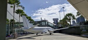 Petit avion stationné sous les palmiers devant un terminal d'aéroport