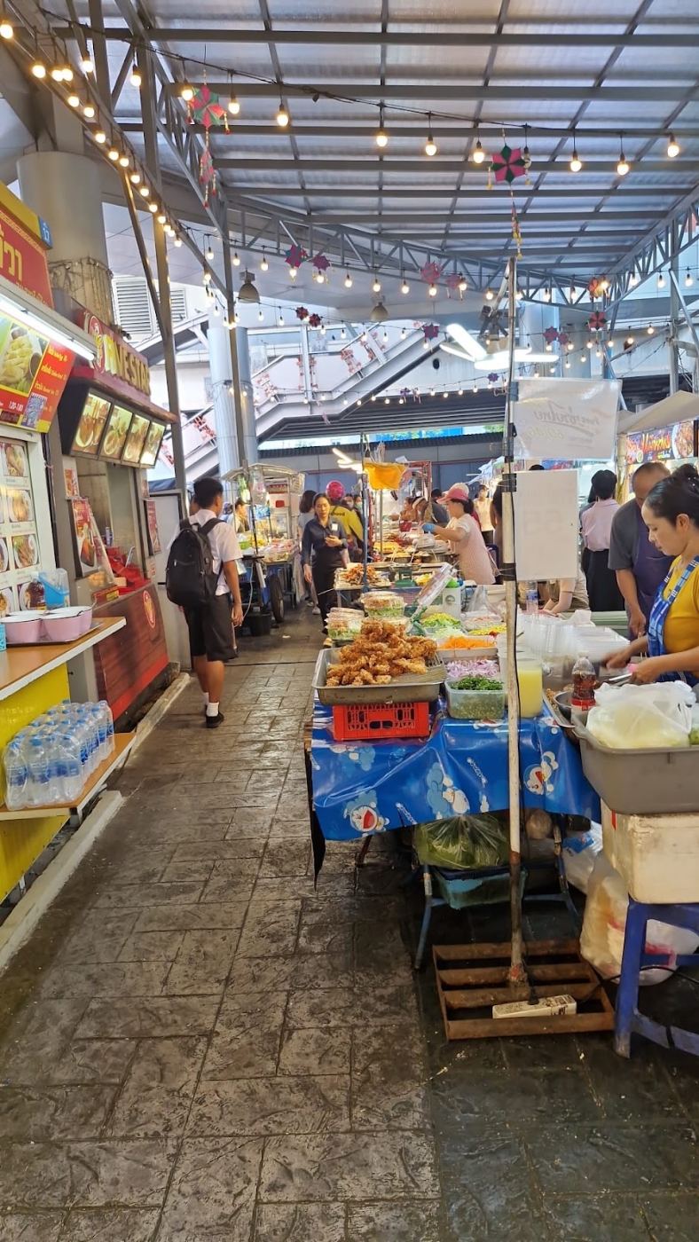 Allée d'un marché couvert à Bangkok, étals de fruits et de snacks