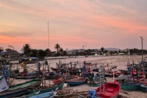 Bateaux de pêche colorés sur une plage de Thaïlande sous un ciel rose